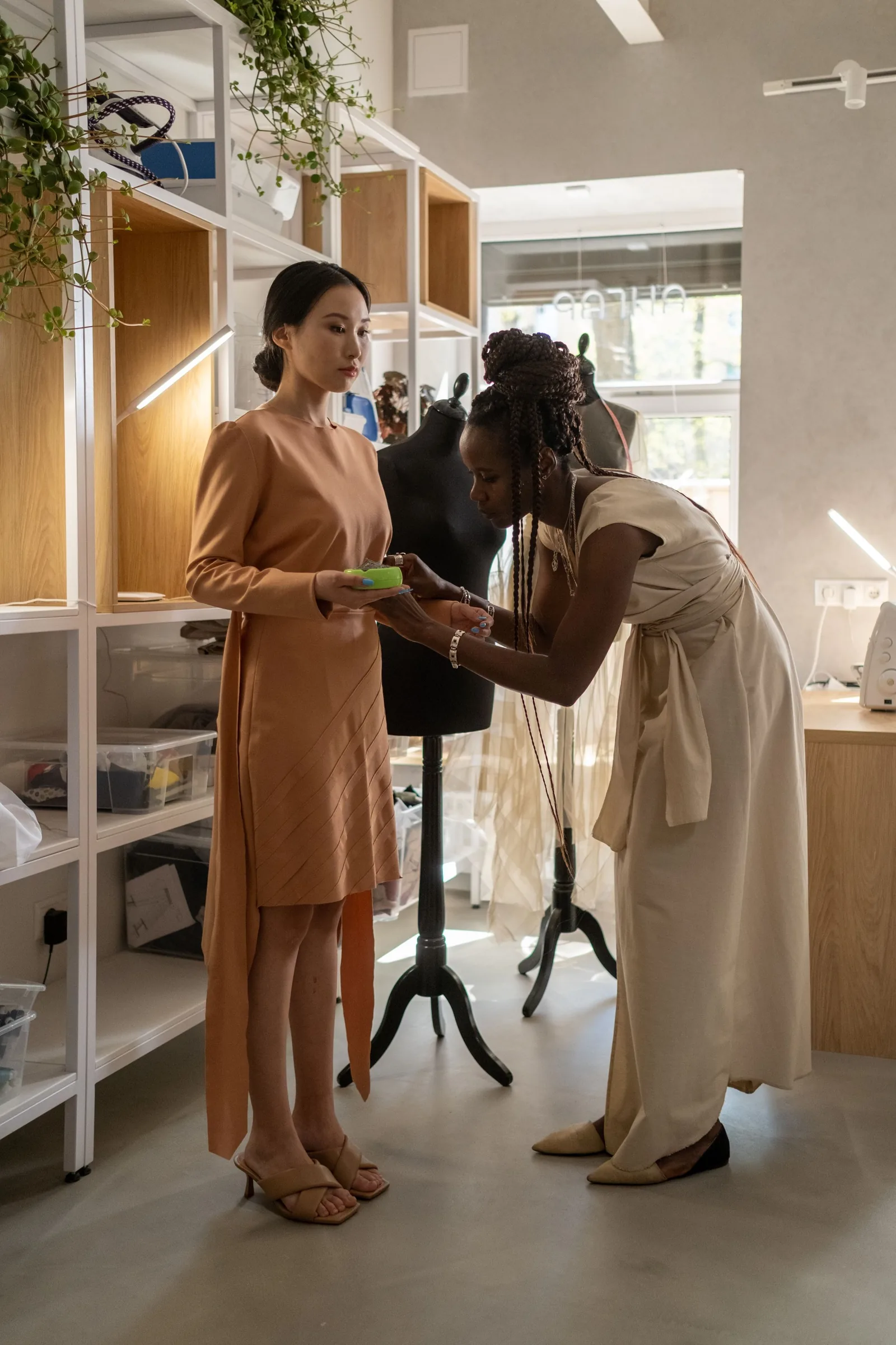 A designer fitting a dress on a client in the atelier