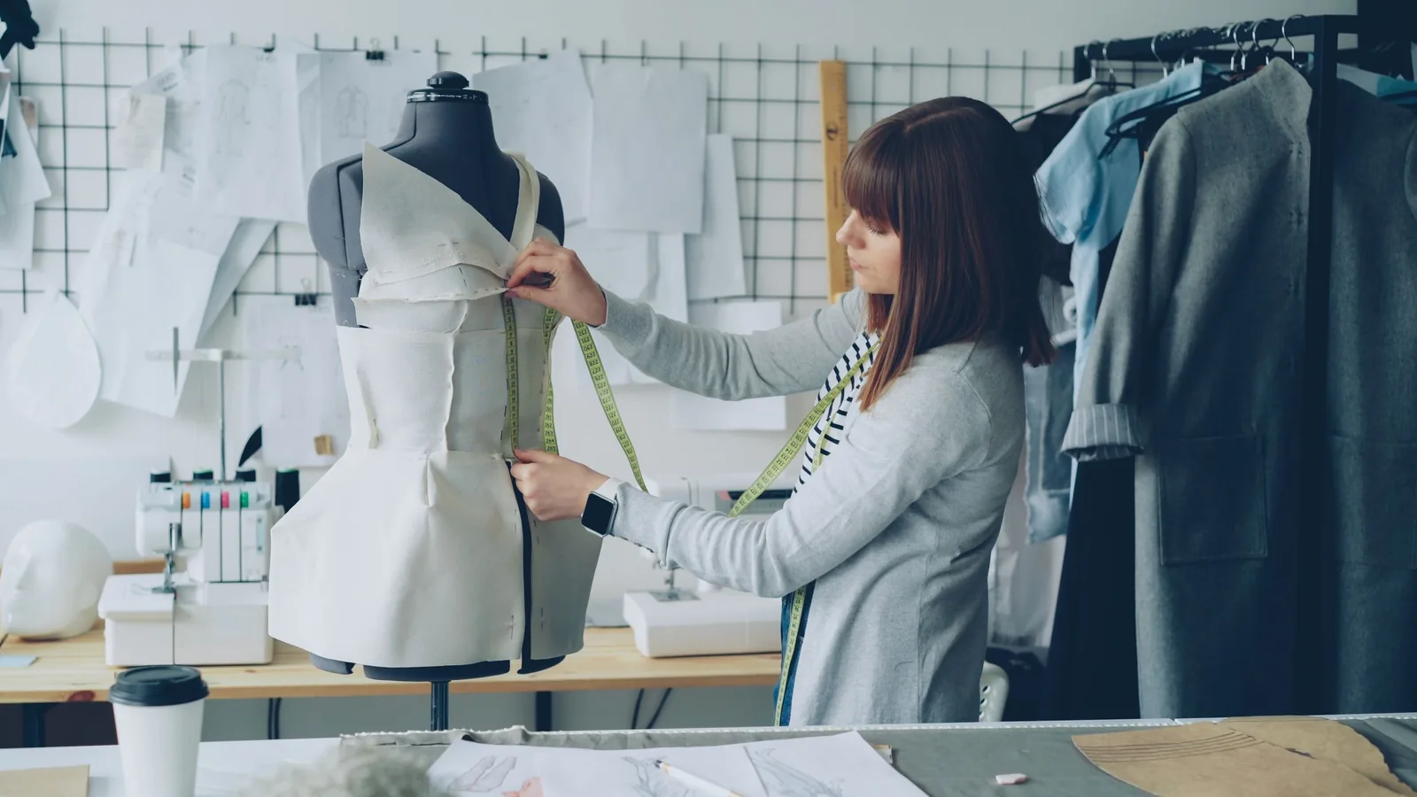 A designer pinning a dress on a mannequin