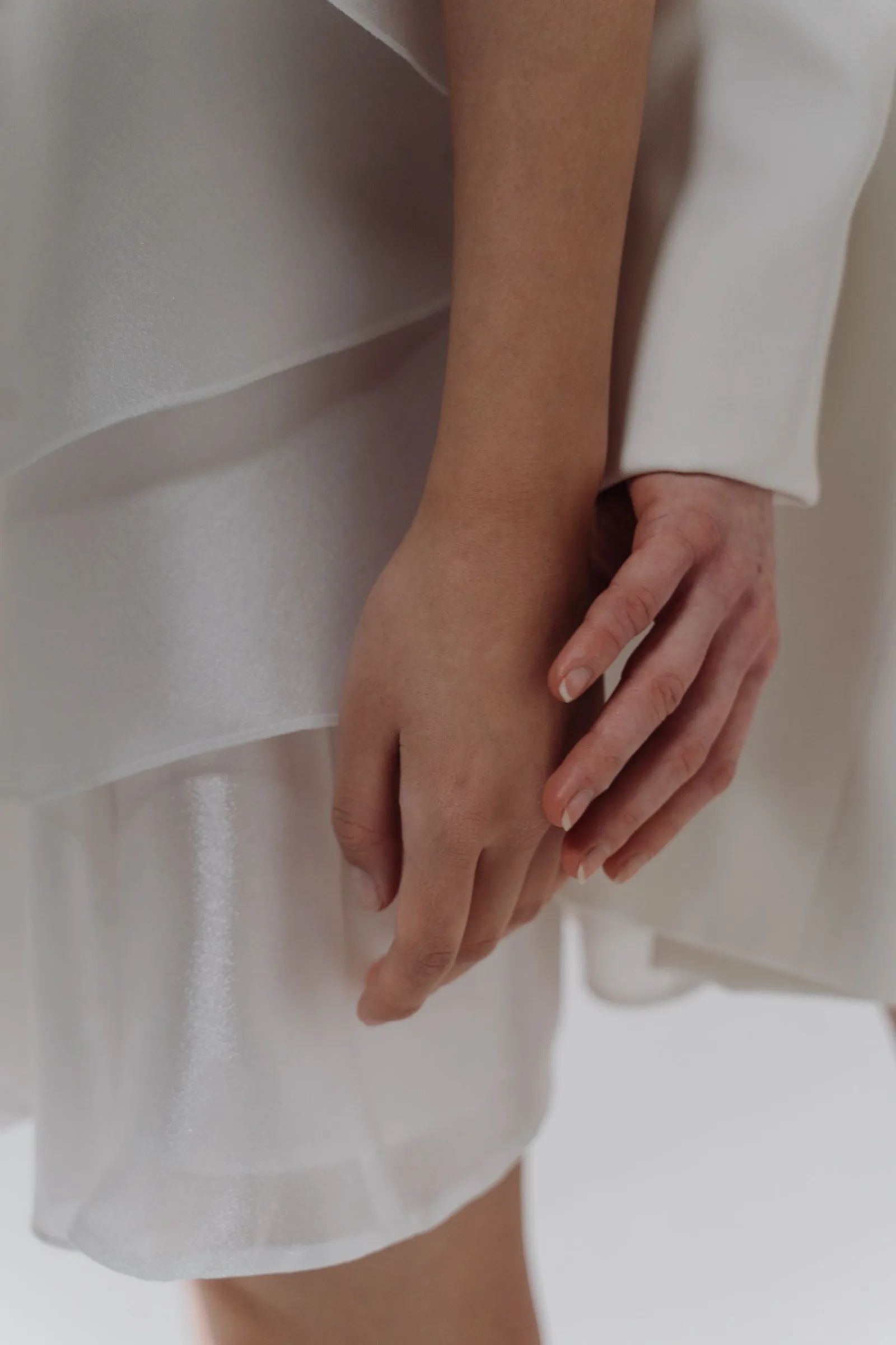 Two hands resting on soft white fabric