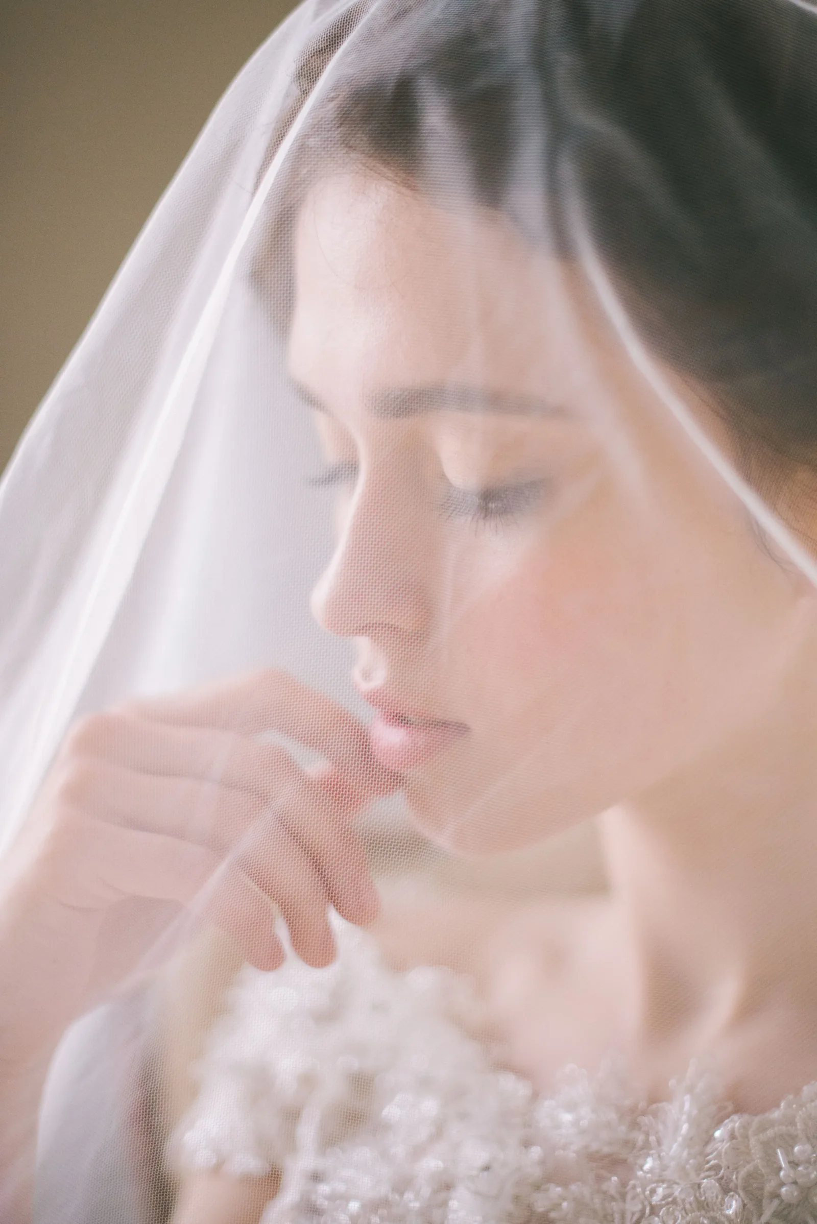 A bride looking down through a sheer veil